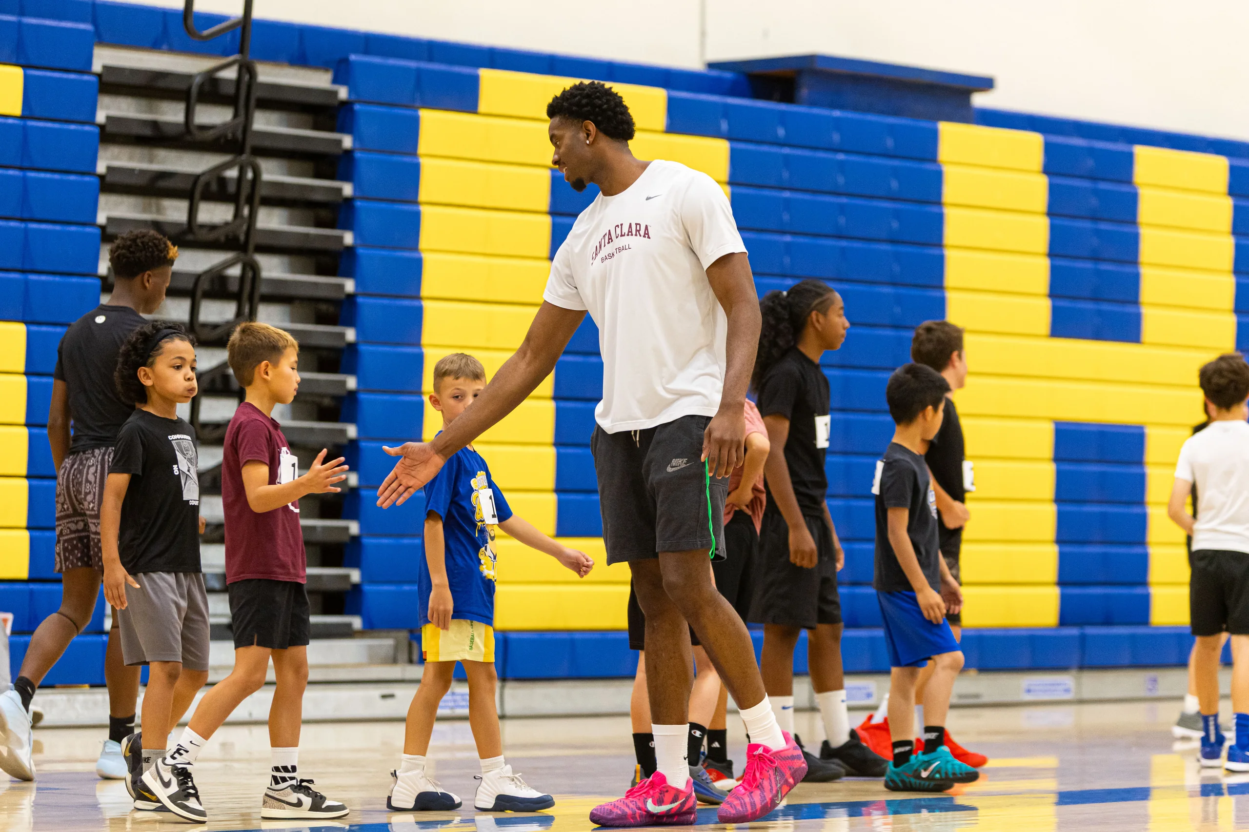 A Santa Clara University player leads a dribbling drill for young campers at the 2026 men's basketball camp