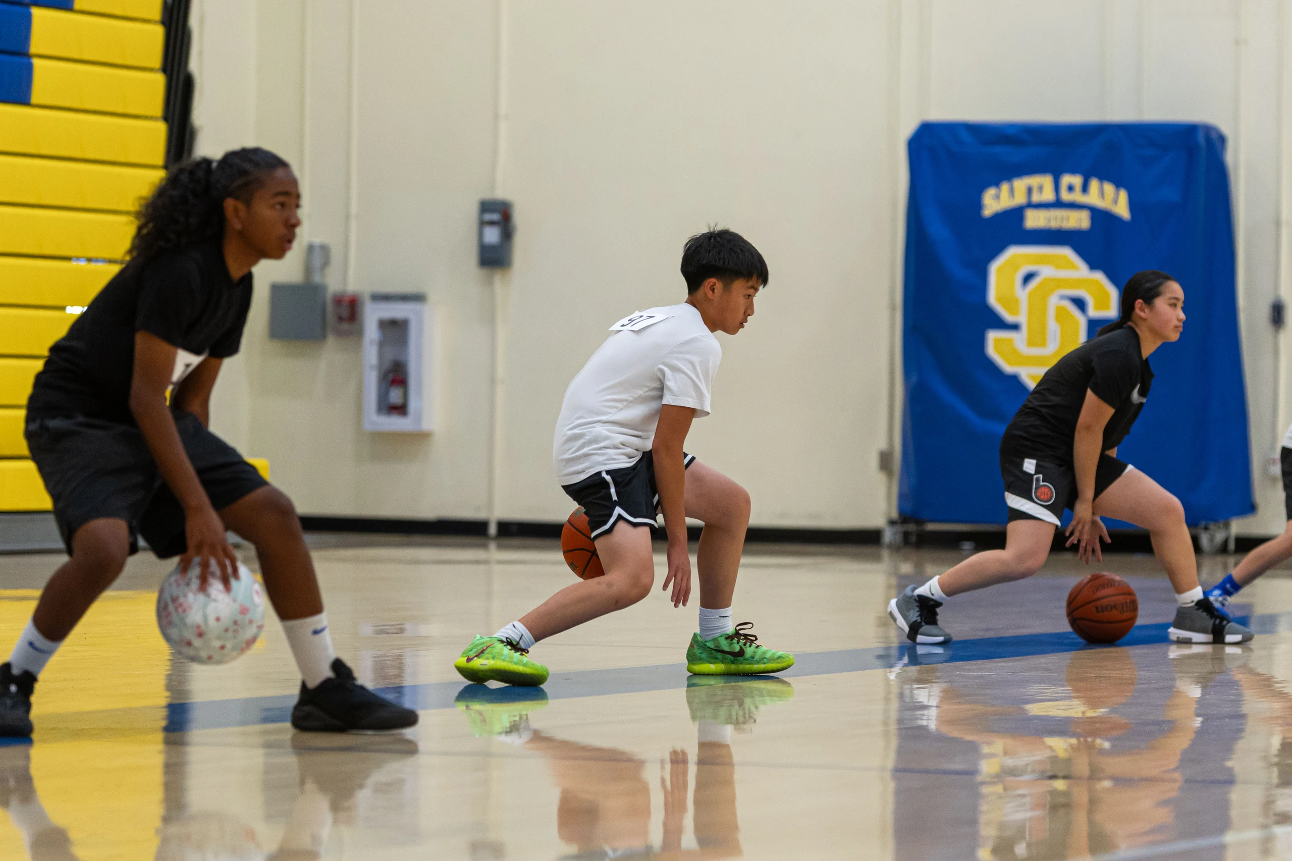 A Santa Clara University player coaches a camper on the court
