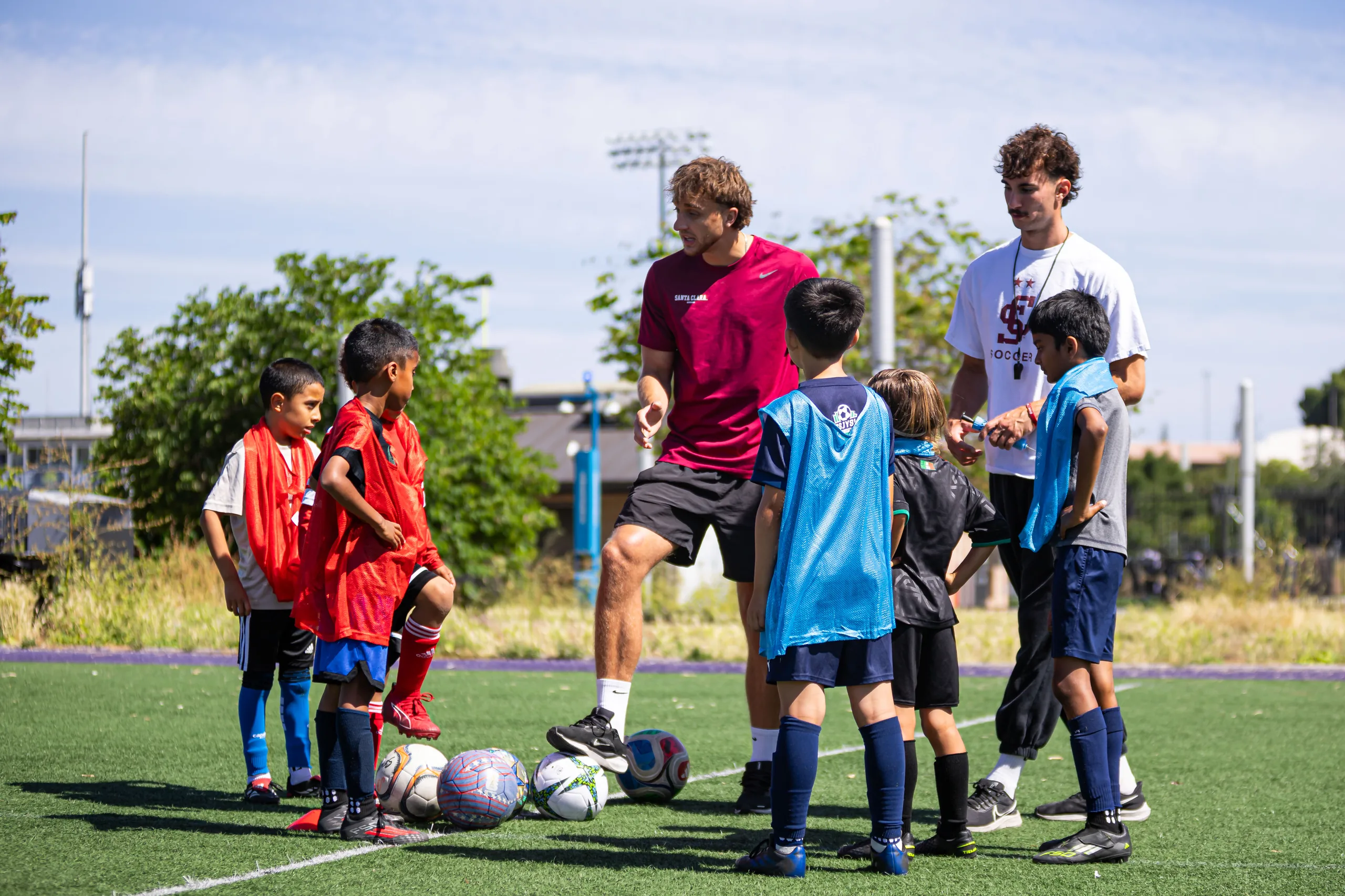 A Santa Clara University player coaches young campers at the 2026 men's soccer clinic