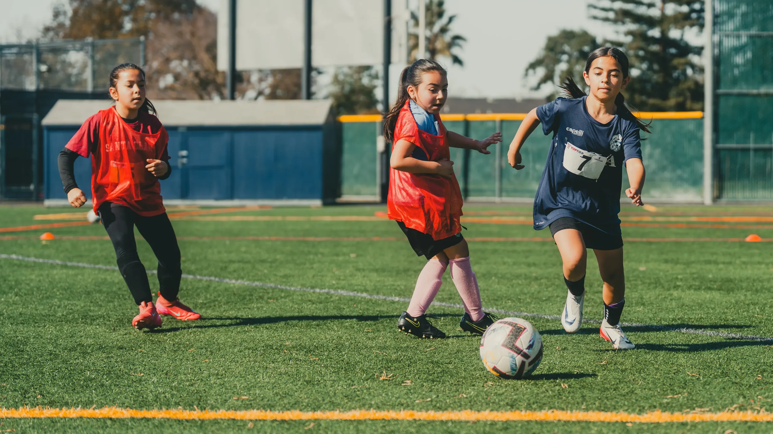 Young players competing for the ball at a Santa Clara women's soccer camp
